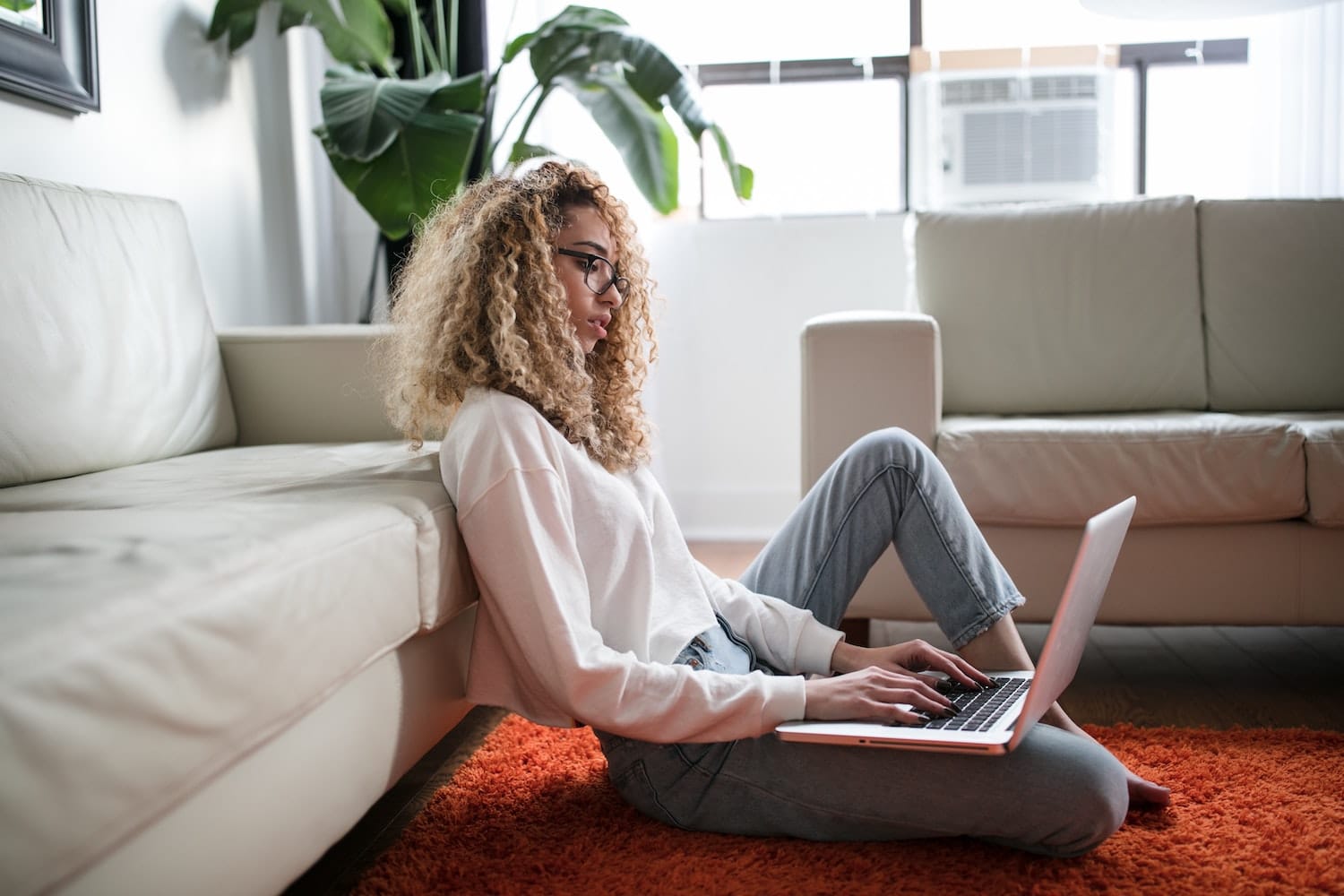 Photo of woman sitting on the floor typing on her laptop