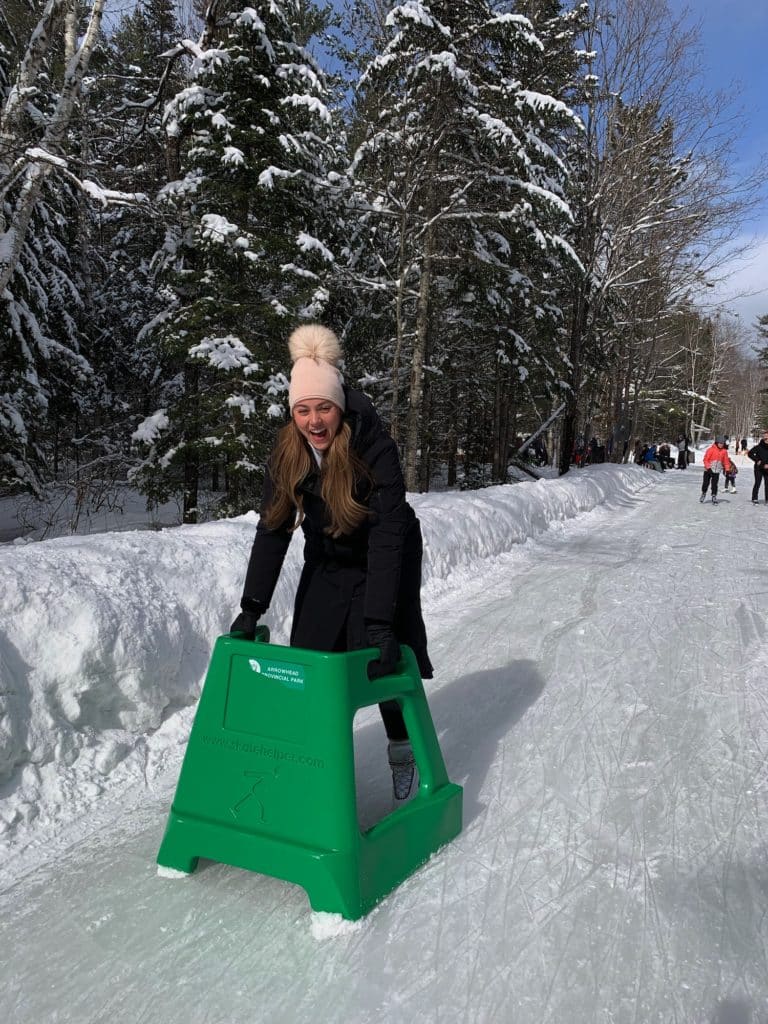 Woman in her twenties skating and smiling using an assisted device