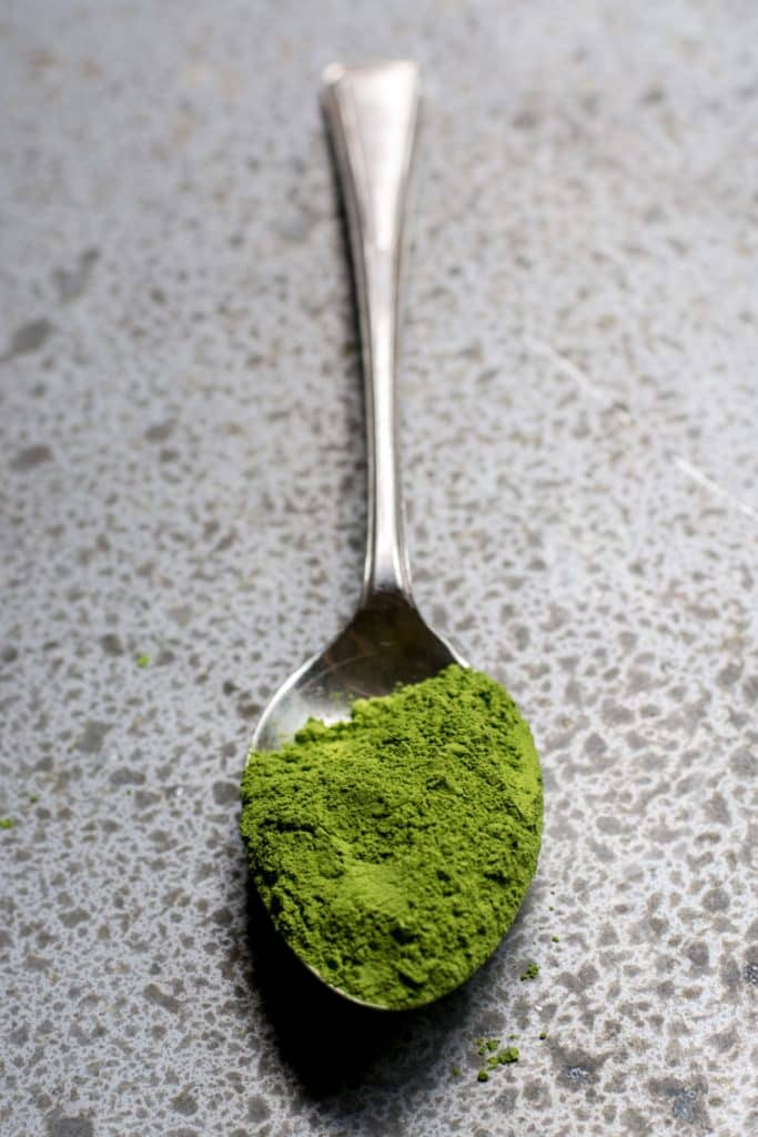 a spoon with powdered athletic greens on a counter.