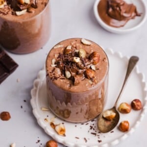 Nutella overnight oats in glass jars, topped with crushed hazelnuts.