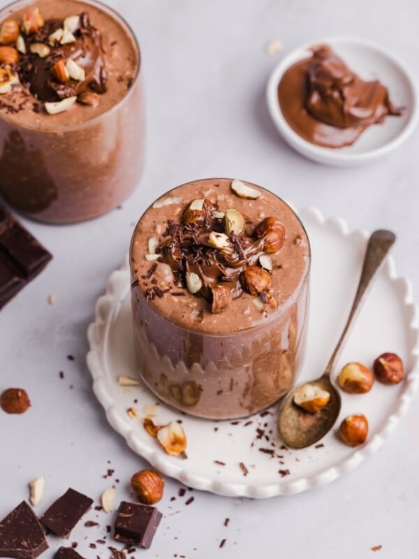 Nutella overnight oats in glass jars, topped with crushed hazelnuts.