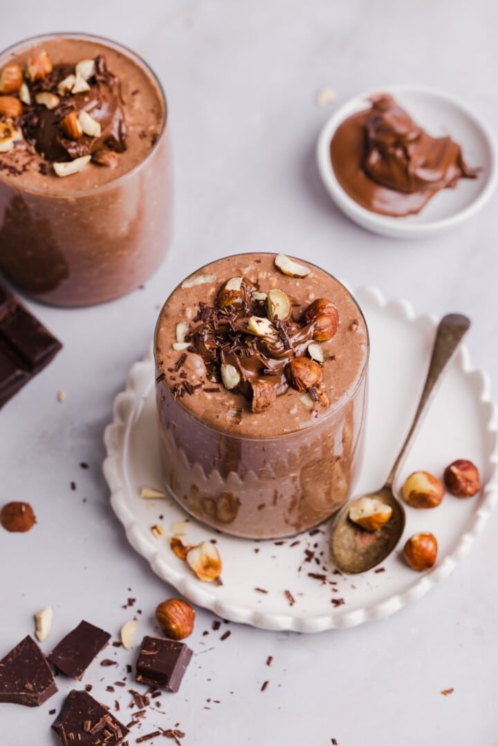 Nutella overnight oats in glass jars, topped with crushed hazelnuts.