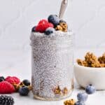 Protein chia pudding topped with berries and granola, in a glass jar