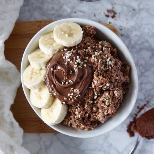 Overhead photos of chocolate overnight oats in a white bowl topped with nutella and banana. Bowl on a white marble counter with ingredients displayed.