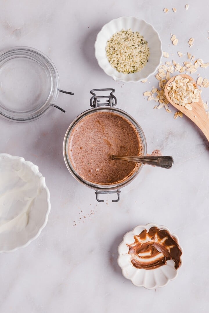 Nutella overnight oats stirred in a glass jar.