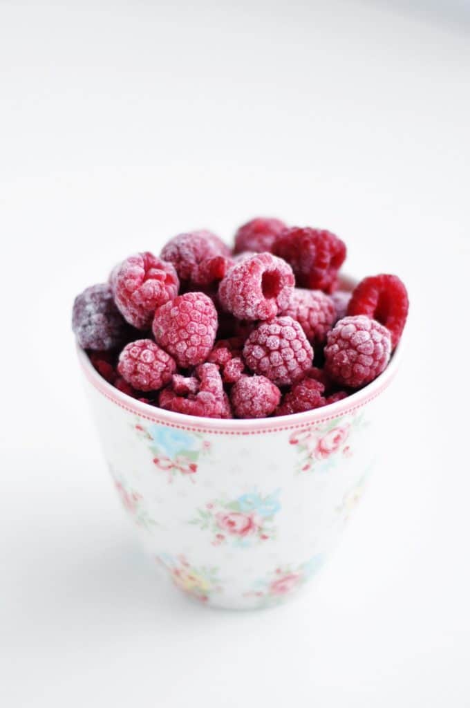 A ceramic tea cup filled with a mixture of frozen berries. 