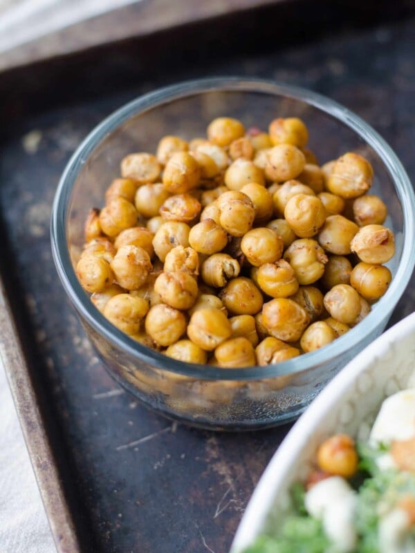 Roasted chickpeas in glass bowl on baking tray.