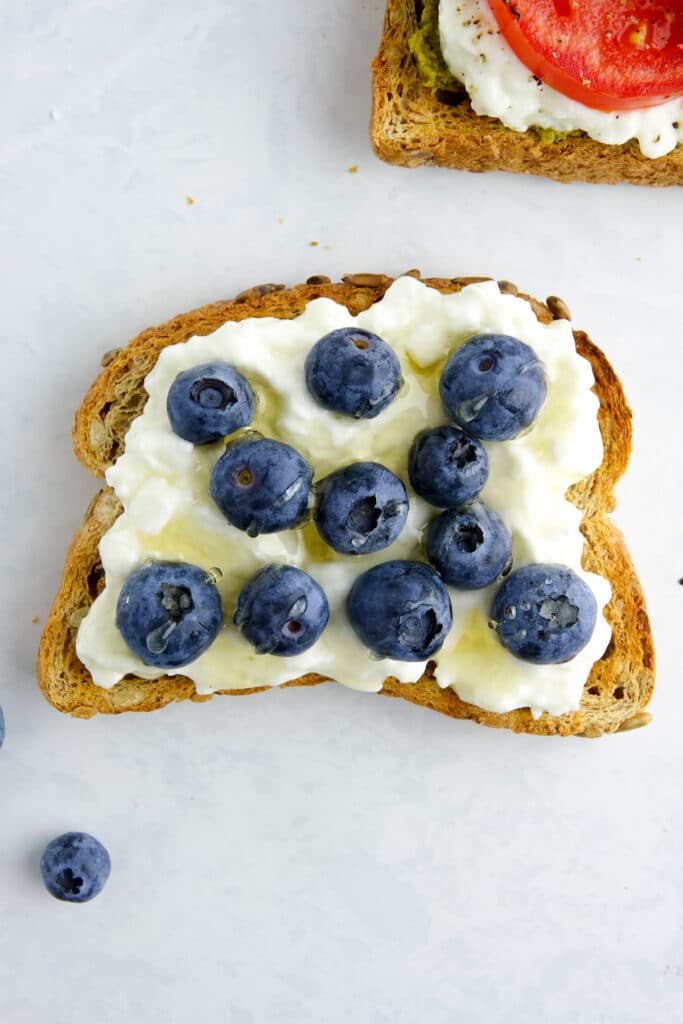 Slice of toast with cottage cheese, blueberries and honey.