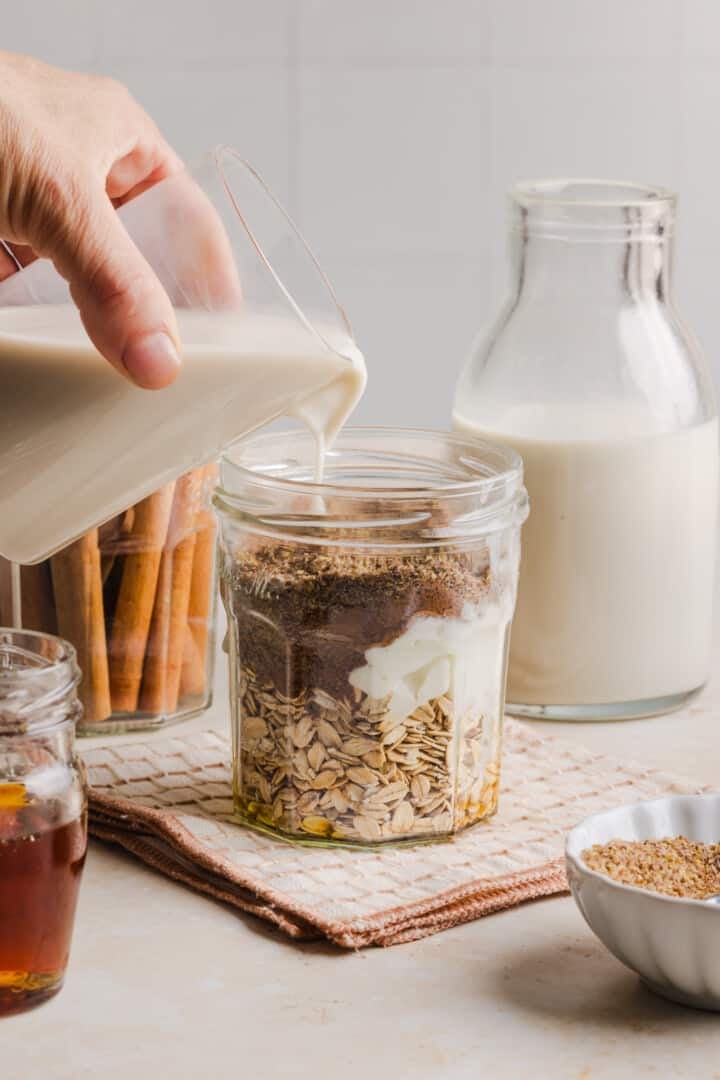 Ingredients for cinnamon roll overnight oats in a glass jar.