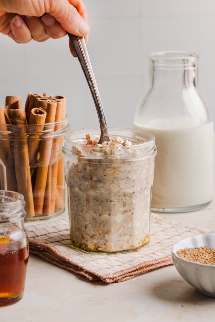 Cinnamon roll overnight oats stirred in a glass jar.