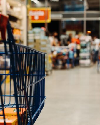 Black grocery cart with blurred background of supermarket.