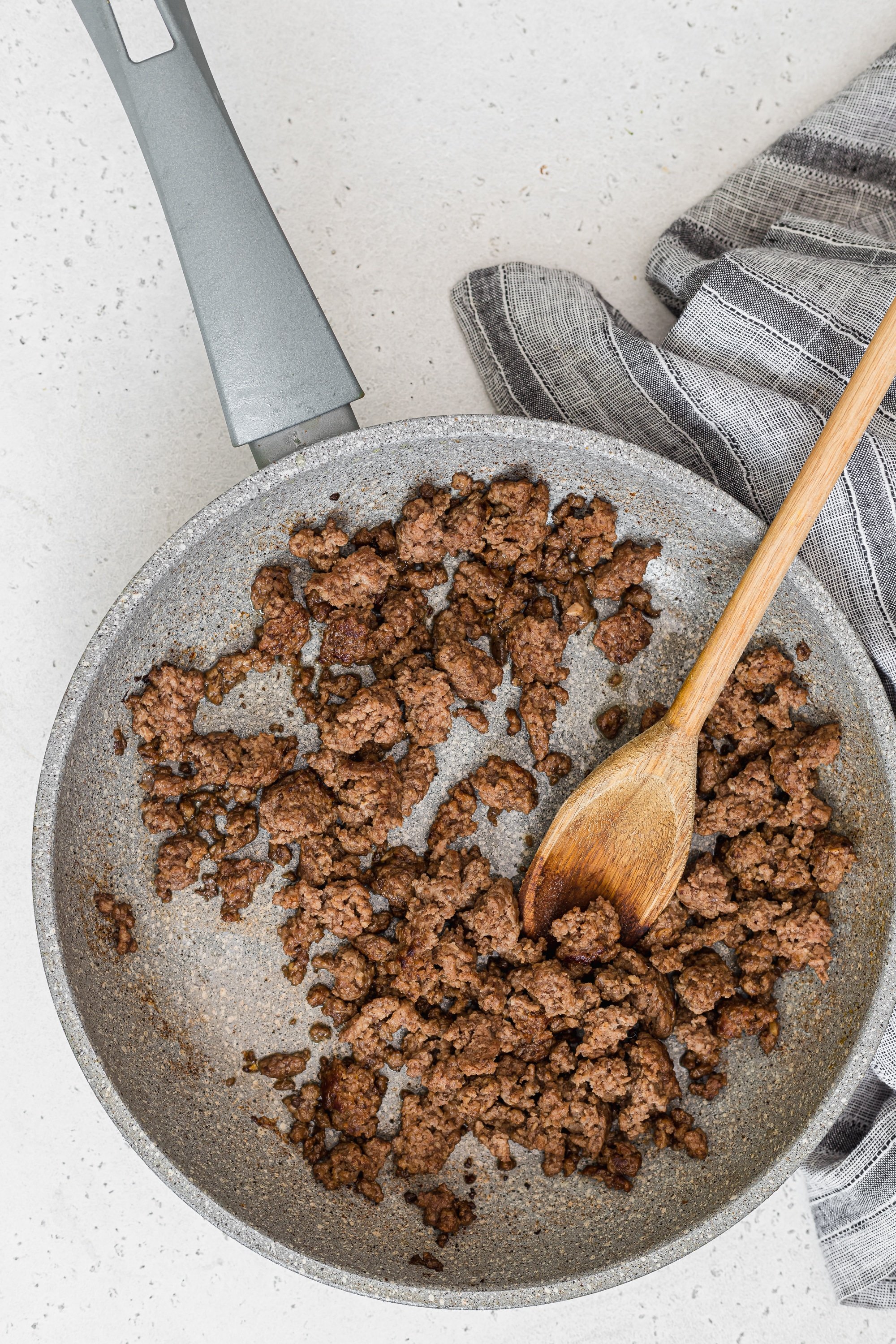 Overhead image of browned ground beef in a grey pan.
