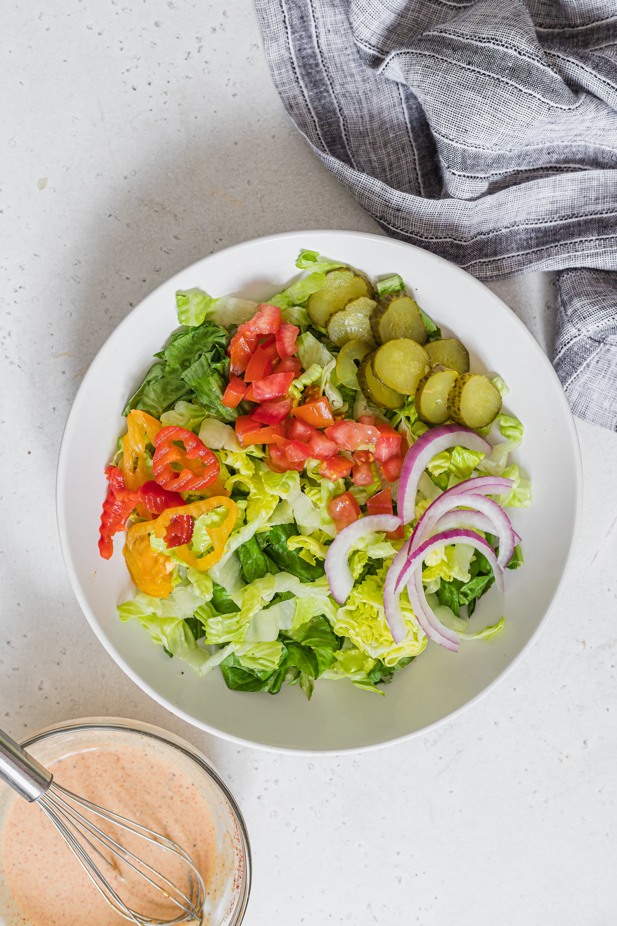 Overhead image of salad ingredients being assembled in a bowl.
