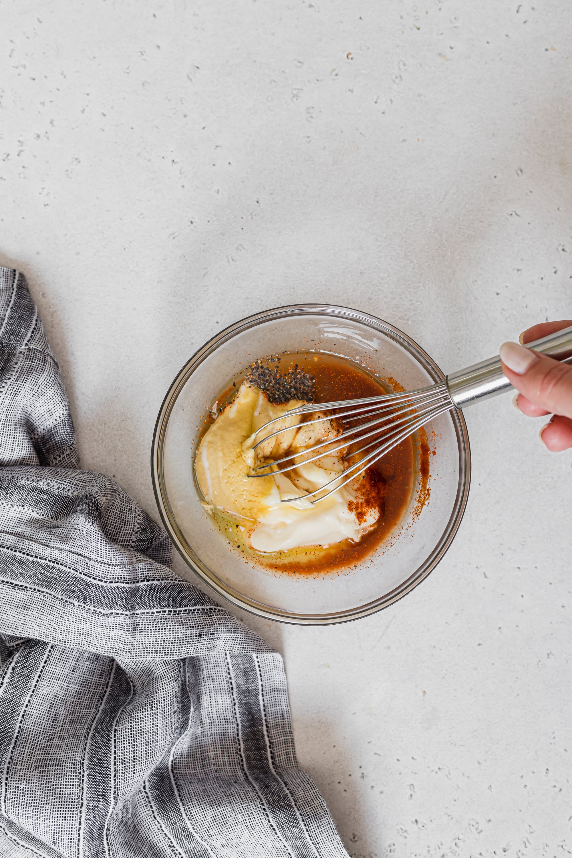 Birdseye image of salad dressing being whisked in a glass bowl.