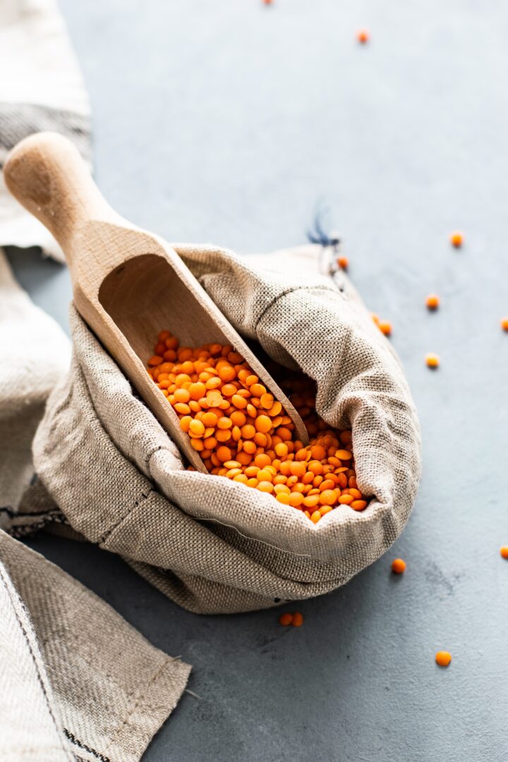 Lentils in an open fabric bag with a scoop sticking out of it.