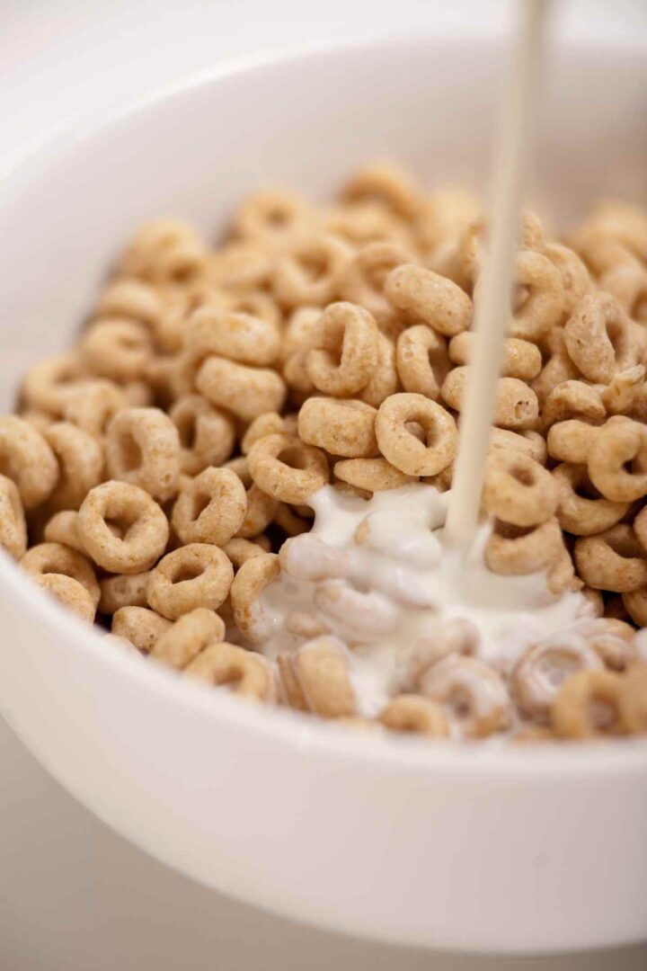 cereal with milk being poured in a white bowl