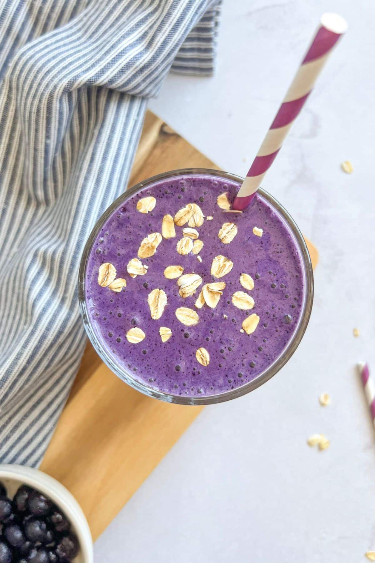 Blueberry protein smoothie in a glass with a straw.