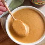 3 Ingredient peanut sauce in a small bowl with a hand spooning the sauce