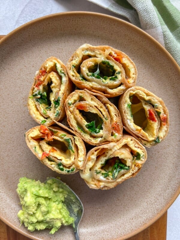 breakfast pinwheels on a plate with mashed avocado
