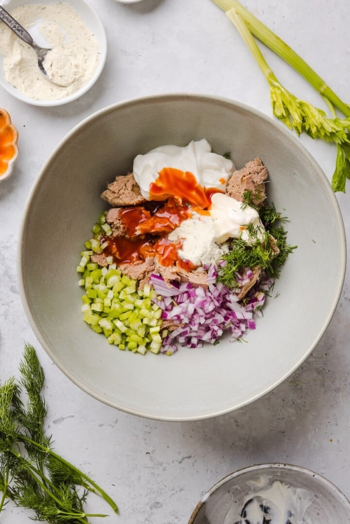 Ingredients for buffalo tuna salad in a white bowl, unmixed.