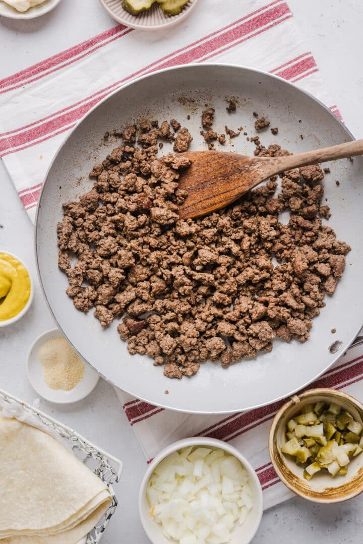 Browned and crumbled beef in a large white pan.