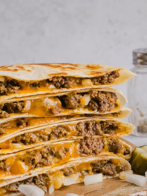 Cheeseburger quesadillas sliced and stacked on a wood cutting board.