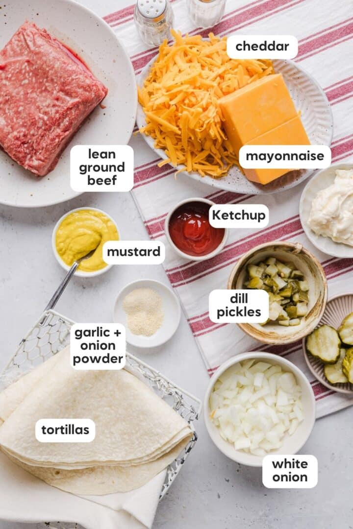 Ingredients for cheeseburger quesadillas displayed in small bowls on a marble counter.