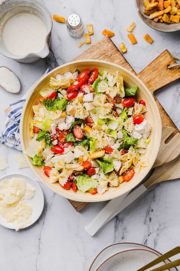 Un-dressed chicken caesar pasta salad in a large bamboo mixing bowl.