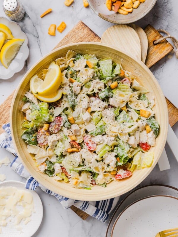 Chicken caesar pasta salad tossed in a large bamboo mixing bowl.