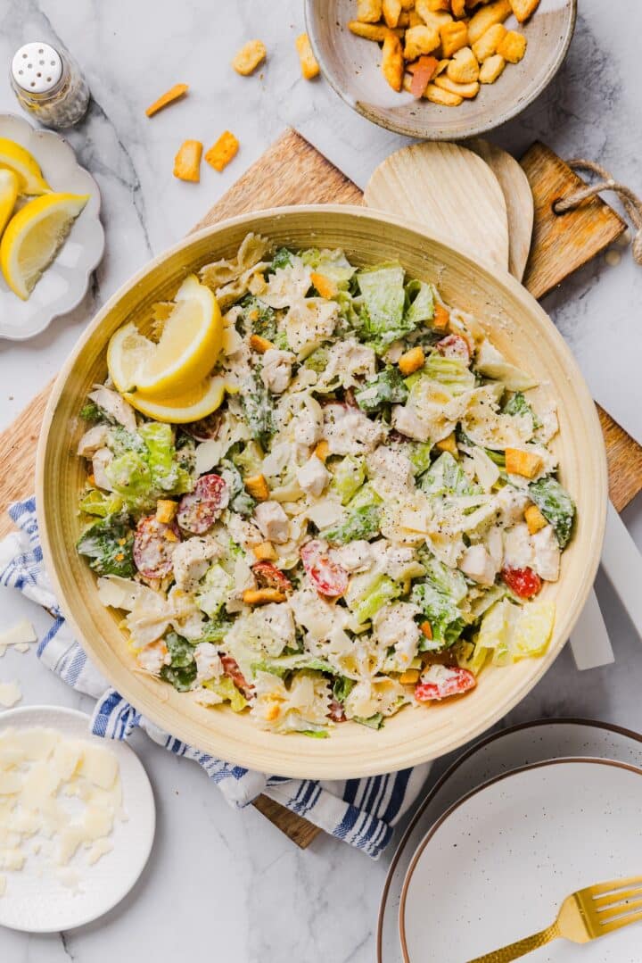 Chicken caesar pasta salad tossed in a large bamboo mixing bowl.