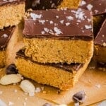 Chocolate peanut butter protein bars stacked on brown parchment paper.
