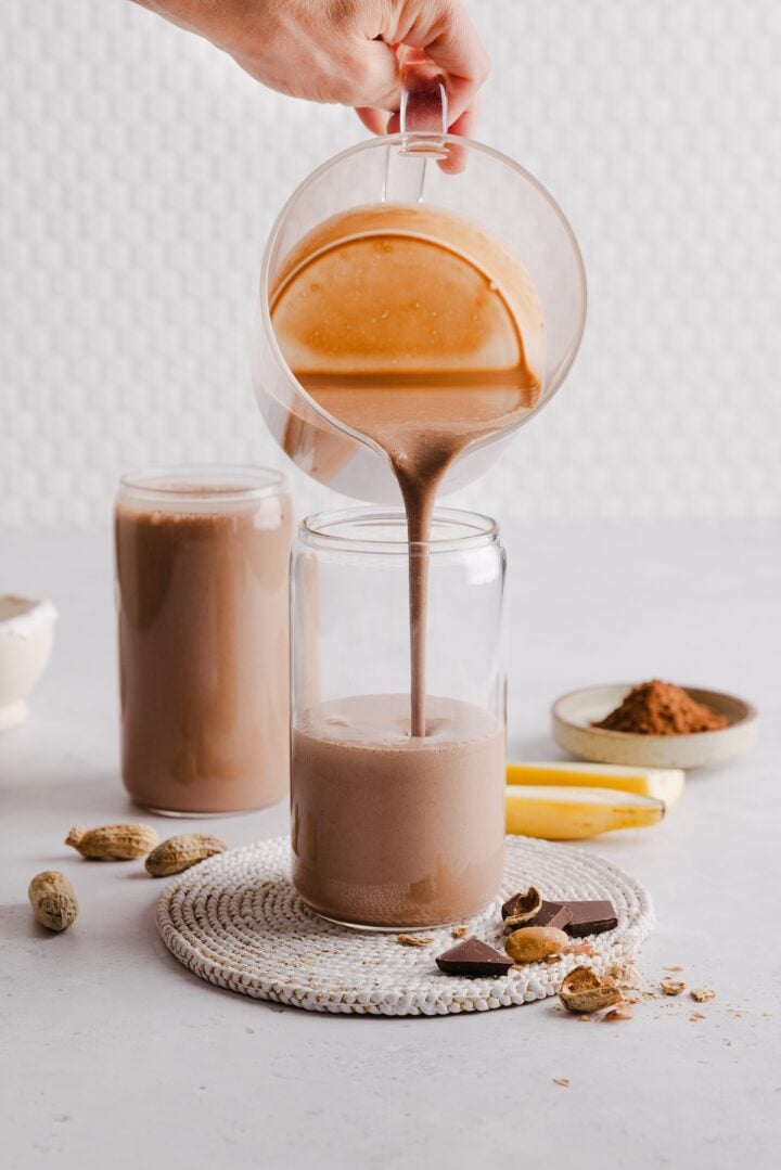 Chocolate peanut butter protein smoothie being poured into a cup.