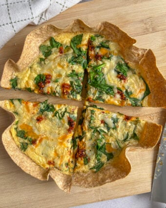 Birdseye photo of a healthy tortilla quiche with spinach and chili oil on top, slices in quarters