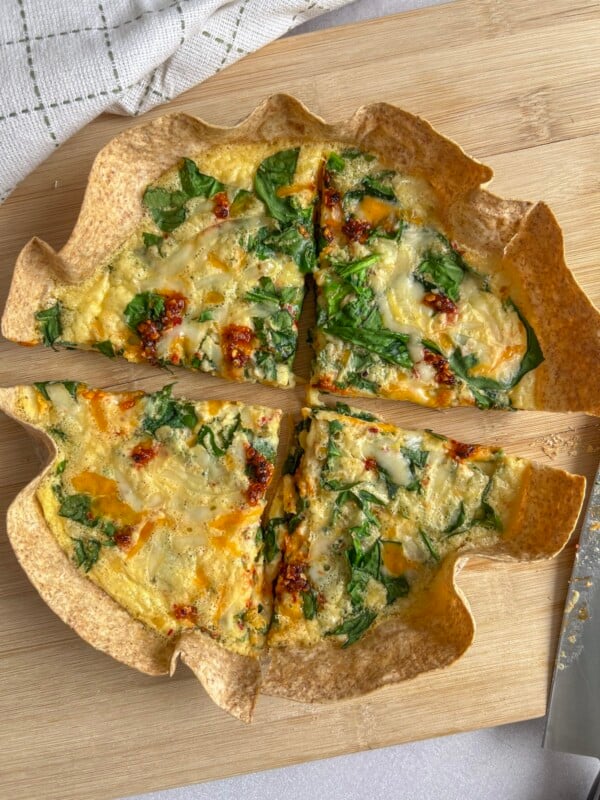Birdseye photo of a healthy tortilla quiche with spinach and chili oil on top, slices in quarters