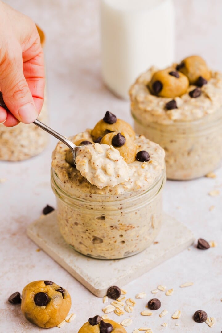 Woman's hands holding a spoon up with cooke dough overnight oats.
