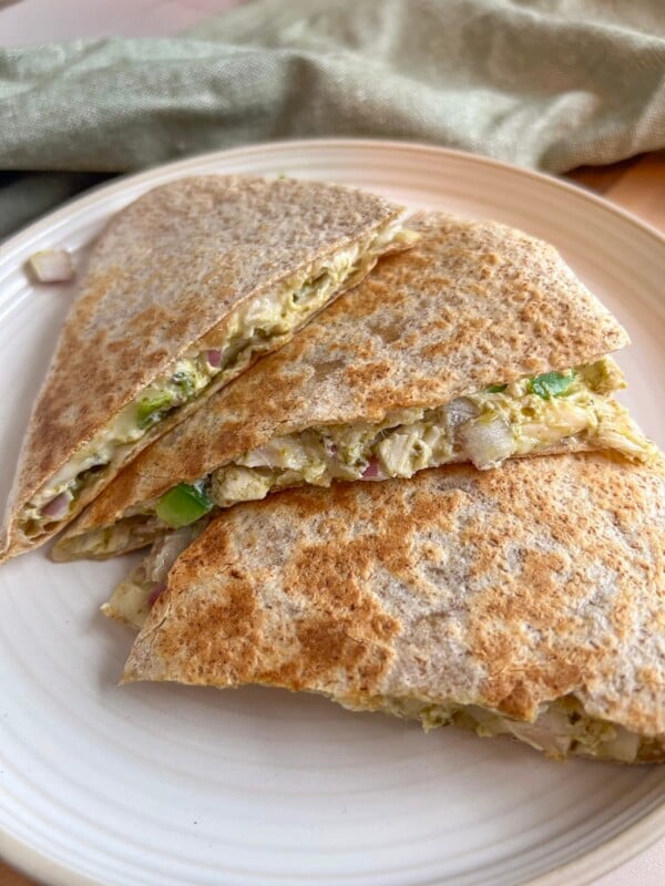 Close-up shot of pesto chicken quesadillas on a plate next to a green kitchen towel