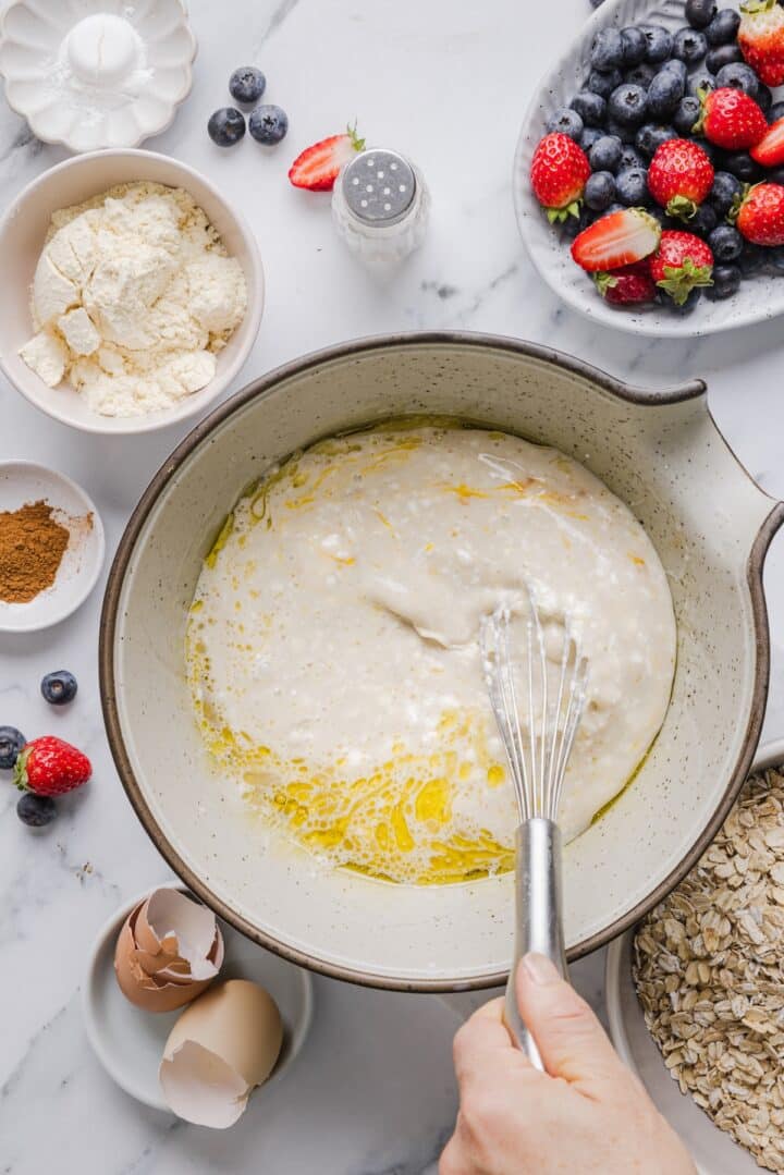 Wet ingredients for protein baked oatmeal being whisked in a large mixing bowl.