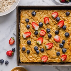 Protein baked oatmeal in a pan with peanut butter and fresh berries.