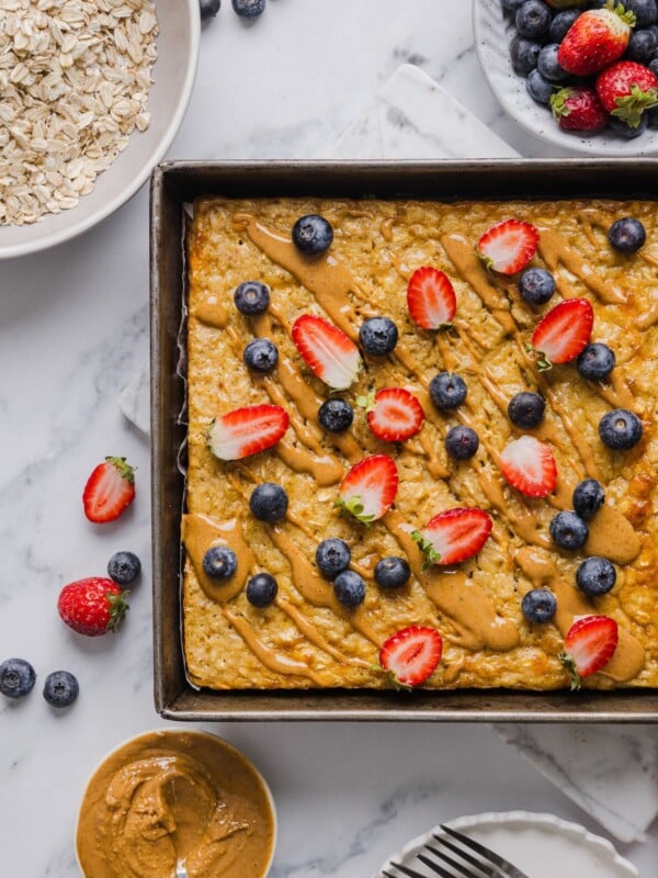 Protein baked oatmeal in a pan with peanut butter and fresh berries.