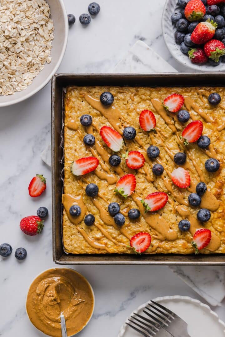 Protein baked oatmeal in a pan with peanut butter and fresh berries.