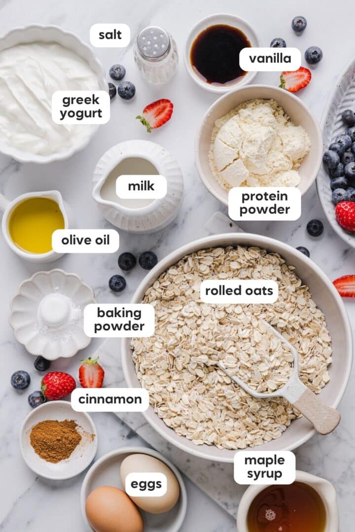 Ingredients for protein baked oatmeal displayed in small bowls on a white kitchen counter.