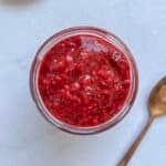 raspberry chia jam in a glass jar on a grey marble counter