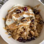 Scrambled oats served with greek yogurt, peanut butter, and berries in a white bowl.