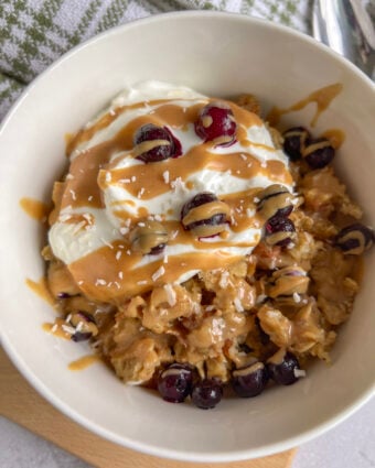 Scrambled oats served with greek yogurt, peanut butter, and berries in a white bowl.