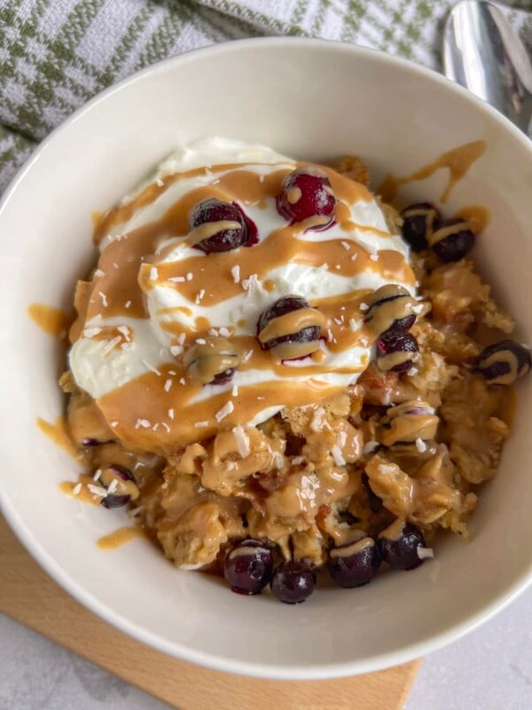 Scrambled oats served with greek yogurt, peanut butter, and berries in a white bowl.