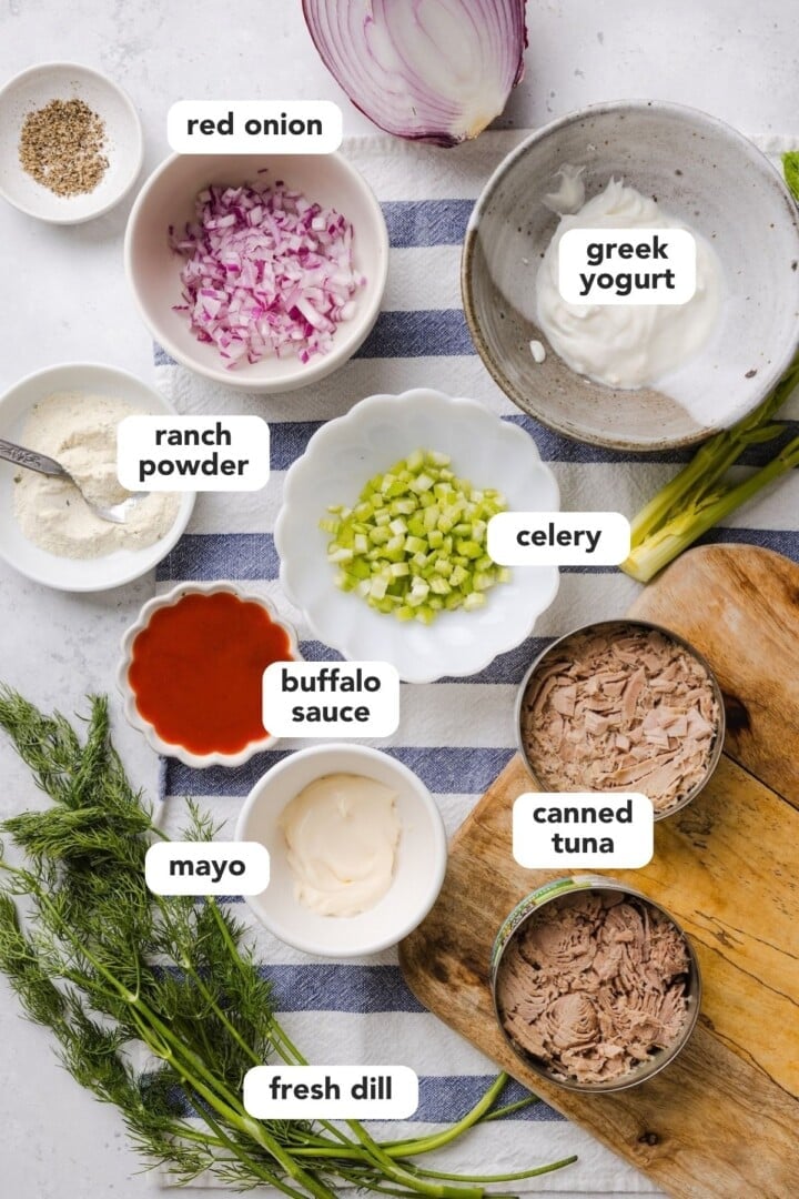 Ingredients for buffalo tuna salad displayed in small bowls on a marble counter.