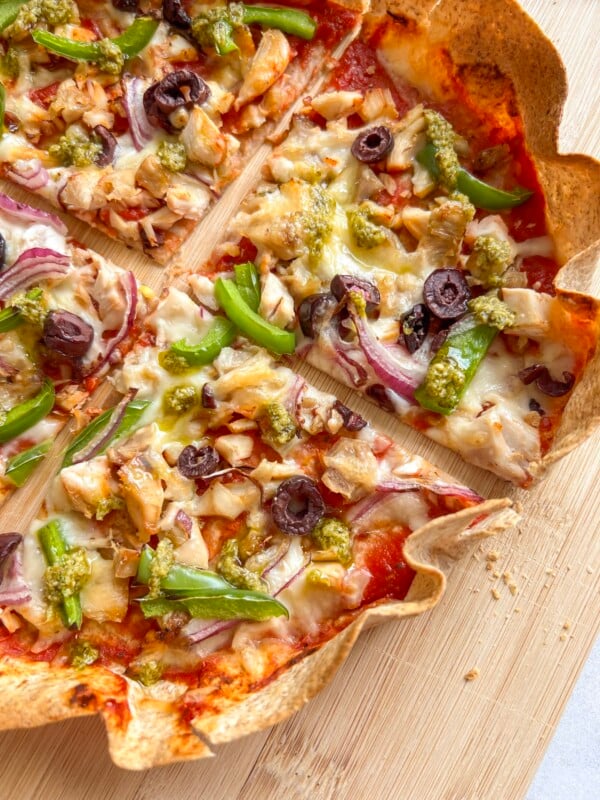 AIr fryer tortilla pizza topped with vegetables and cheese, sliced into quarters