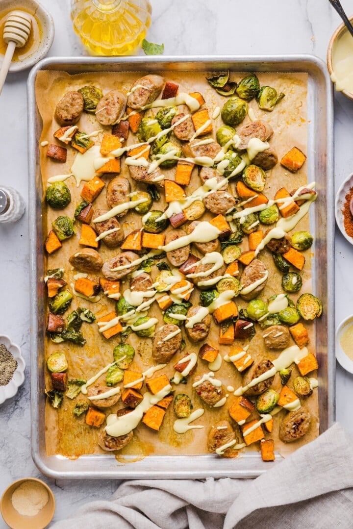 Chicken sausage sheet pan dinner with honey mustard drizzled on top.