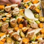 Chicken sausage sheet pan dinner with yogurt honey mustard being drizzled over top.