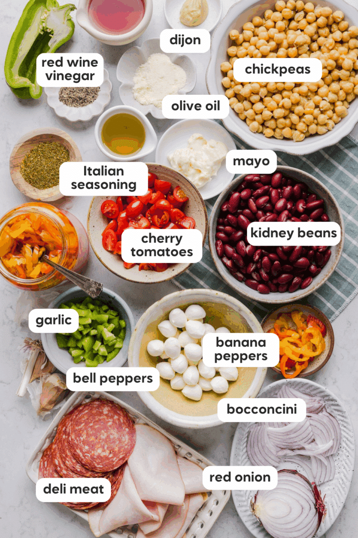 Ingredients for Italian grinder bean salad displayed in small bowls on a marble counter.
